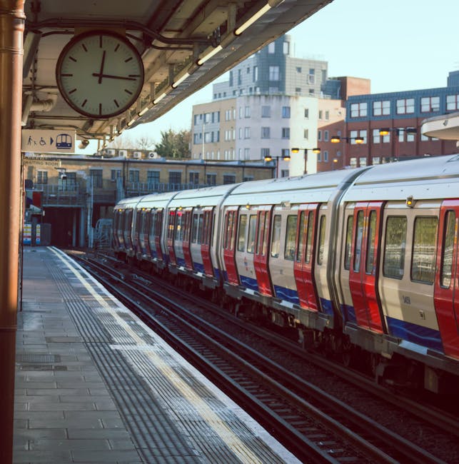 Wide view of multiple train tracks at a railway station with two modern yellow and grey electric trains parked side by side. The tracks are made of steel rails mounted on wooden sleepers with gravel b